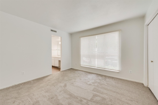 spare room featuring baseboards, light carpet, and visible vents