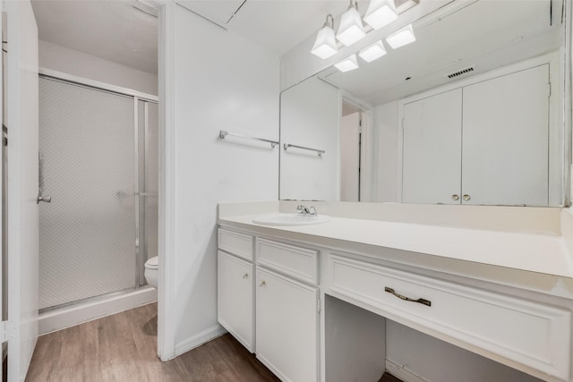 full bath featuring wood finished floors, a stall shower, toilet, and vanity