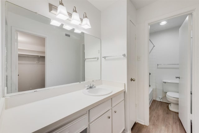 bathroom with visible vents, wood finished floors, vanity, toilet, and washtub / shower combination