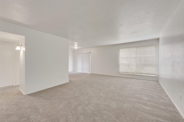 spare room featuring carpet floors and baseboards