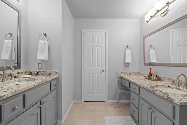 bathroom featuring baseboards, a sink, tile patterned floors, and two vanities