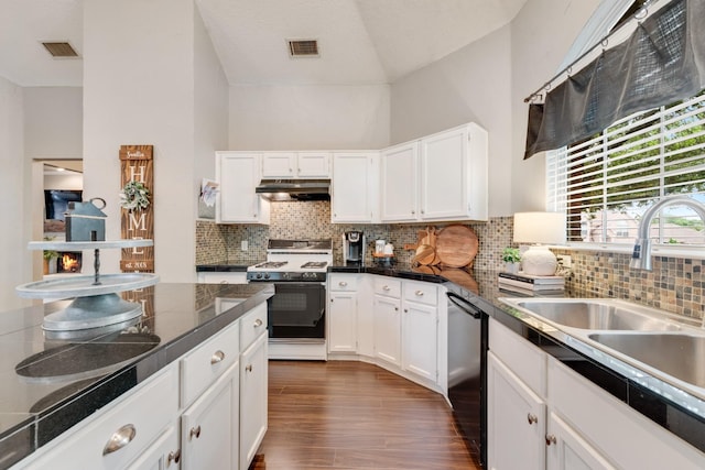 kitchen with under cabinet range hood, gas range oven, visible vents, a sink, and vaulted ceiling
