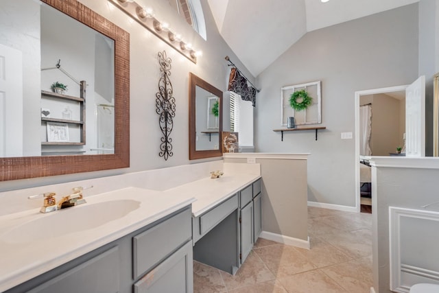 bathroom featuring a sink, double vanity, lofted ceiling, and tile patterned floors