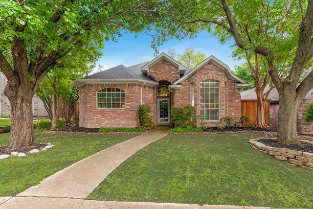 view of front facade featuring brick siding, a front lawn, and fence