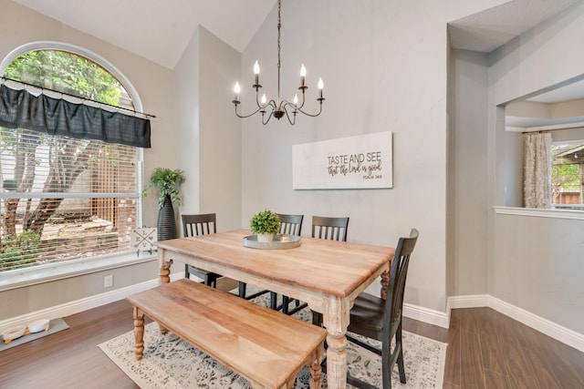 dining room featuring a chandelier, baseboards, vaulted ceiling, and wood finished floors
