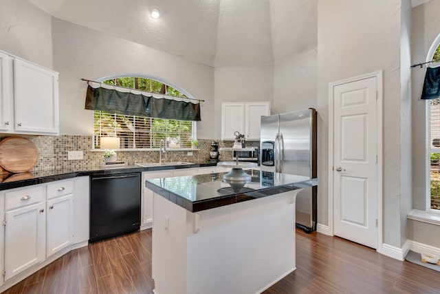 kitchen with stainless steel refrigerator with ice dispenser, white cabinets, tasteful backsplash, a sink, and dishwasher