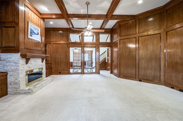 908 Willow Brook Dr, Allen, TX 75002 - unfurnished living room with ceiling fan, a stone fireplace, wood walls, beam ceiling, and carpet floors