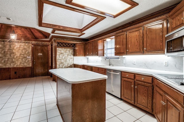 908 Willow Brook Dr, Allen, TX 75002 - kitchen featuring a sink, light countertops, wood walls, stainless steel appliances, and visible vents