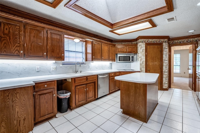 908 Willow Brook Dr, Allen, TX 75002 - kitchen featuring a textured ceiling, visible vents, brown cabinets, a sink, and stainless steel appliances