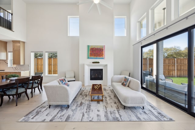 1 Mimosa Pl, Richardson, TX 75080 - living room with light wood-style floors, a ceiling fan, a glass covered fireplace, and a towering ceiling