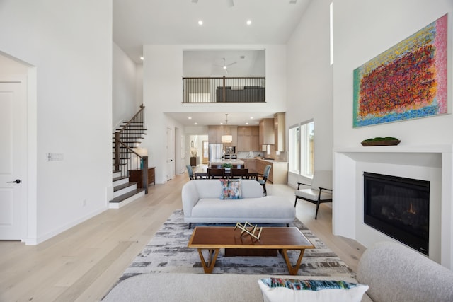 1 Mimosa Pl, Richardson, TX 75080 - living room featuring light wood finished floors, a glass covered fireplace, stairs, baseboards, and a towering ceiling