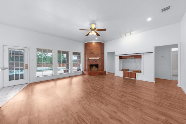 unfurnished living room featuring a fireplace, a ceiling fan, baseboards, wood finished floors, and visible vents
