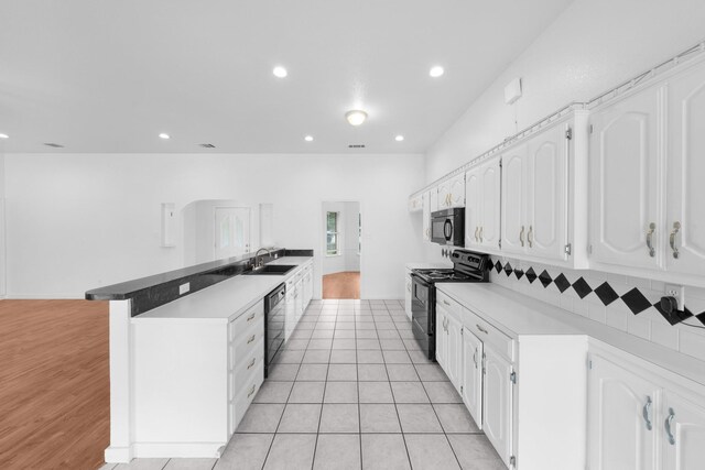 kitchen with a sink, white cabinets, and black appliances