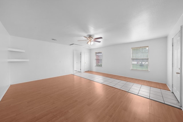 unfurnished living room with visible vents, ceiling fan, and wood finished floors