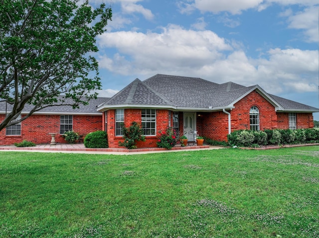 single story home with brick siding, a shingled roof, and a front lawn