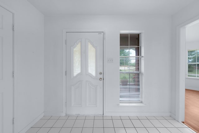 entrance foyer featuring light tile patterned floors, baseboards, and plenty of natural light