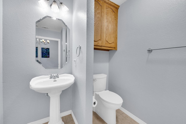 bathroom with a sink, tile patterned floors, baseboards, and toilet