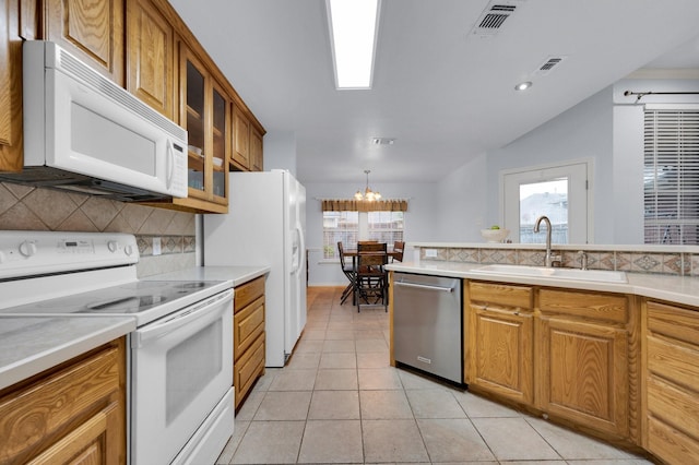 kitchen with a sink, light countertops, backsplash, and white appliances