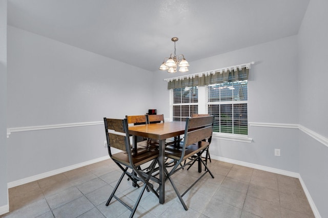 tiled dining space with baseboards and a notable chandelier
