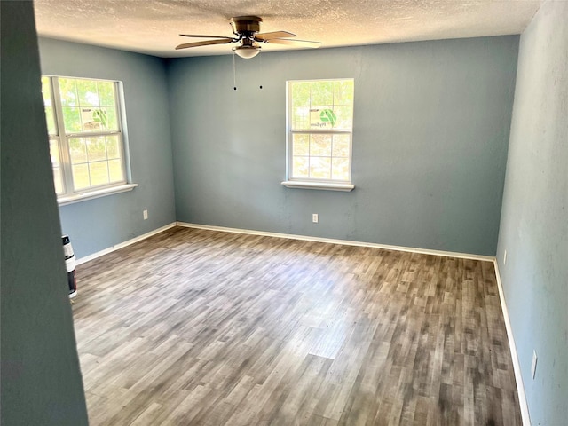 spare room with a textured ceiling, baseboards, wood finished floors, and a ceiling fan