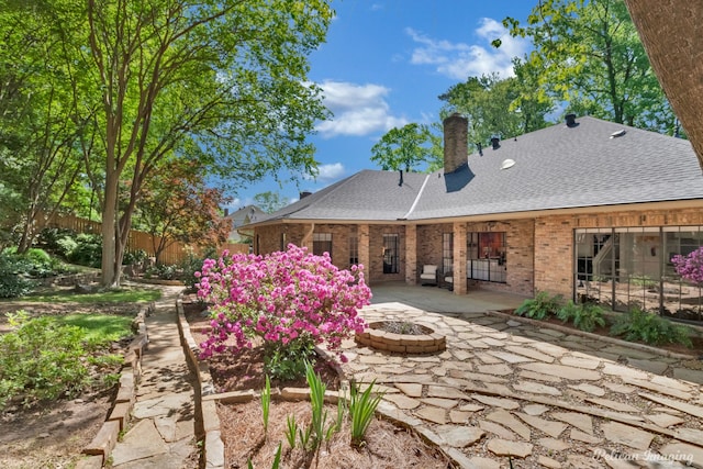 314 Gentilly Cir, Shreveport, LA 71106 - rear view of property with roof with shingles, brick siding, a chimney, a patio, and a fire pit