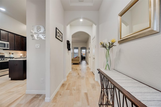 corridor with light wood-style floors and arched walkways