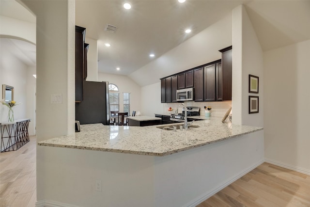 kitchen featuring visible vents, a peninsula, lofted ceiling, light wood-style floors, and appliances with stainless steel finishes