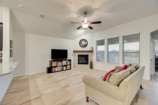 living room with light wood-type flooring, a ceiling fan, a premium fireplace, and visible vents