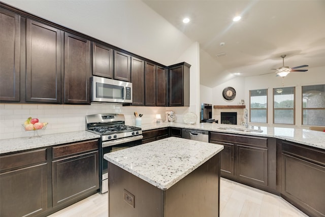 kitchen featuring a sink, lofted ceiling, a ceiling fan, appliances with stainless steel finishes, and backsplash