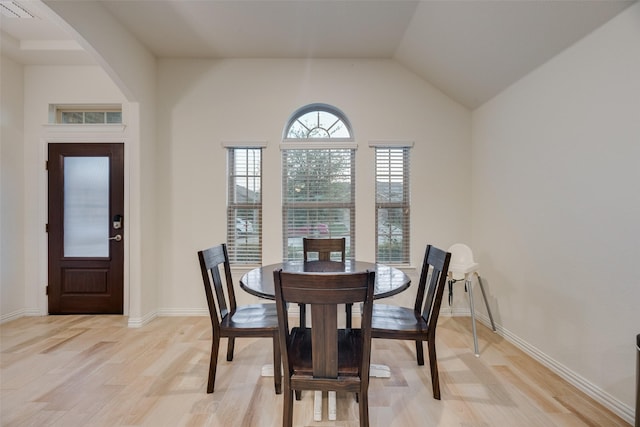 dining room with arched walkways, baseboards, light wood finished floors, and visible vents