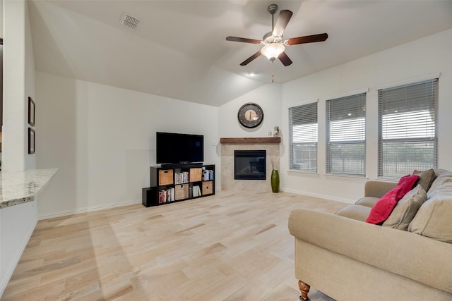 living area with ceiling fan, light wood finished floors, a fireplace, baseboards, and lofted ceiling