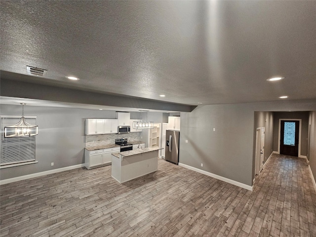 2120 Rw Bivens Ln, Fort Worth, TX 76105 - kitchen featuring stainless steel appliances, a chandelier, a kitchen island, light wood-type flooring, and a textured ceiling
