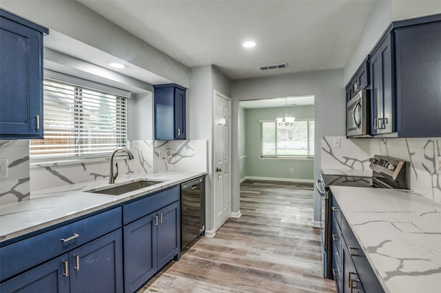 kitchen featuring blue cabinetry, visible vents, appliances with stainless steel finishes, a sink, and a notable chandelier