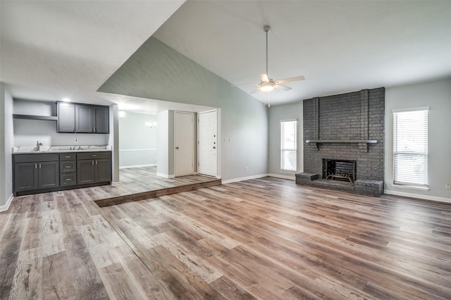 1200 Kesser Dr, Plano, TX 75025 - unfurnished living room with light wood-style flooring, baseboards, ceiling fan, a sink, and a fireplace