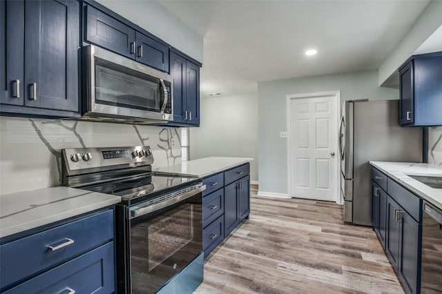 kitchen featuring light wood-style floors, baseboards, recessed lighting, blue cabinets, and appliances with stainless steel finishes