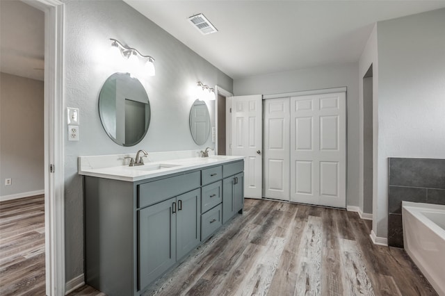 1200 Kesser Dr, Plano, TX 75025 - bathroom featuring a bath, visible vents, wood finished floors, and a sink