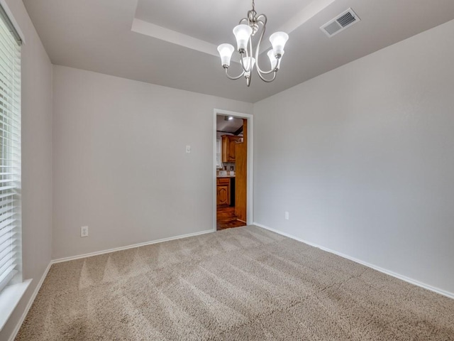carpeted spare room with baseboards, a chandelier, and visible vents