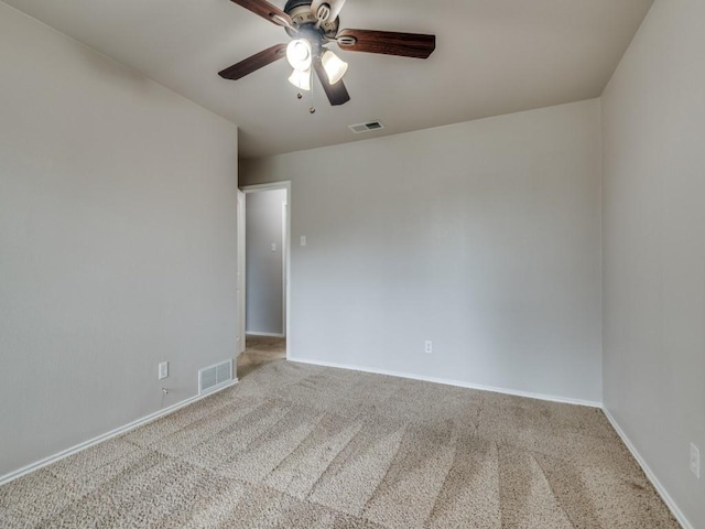 carpeted spare room with visible vents, baseboards, and ceiling fan