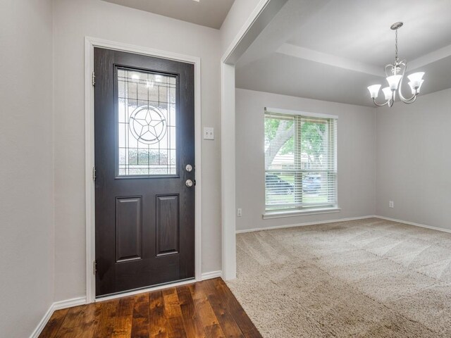 foyer featuring a tray ceiling, an inviting chandelier, baseboards, and wood finished floors
