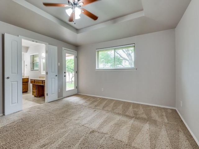 spare room featuring a ceiling fan, baseboards, light colored carpet, and a raised ceiling