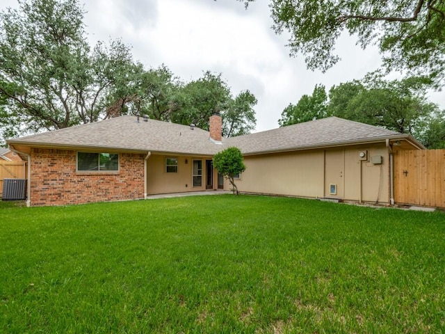 back of property with a lawn, central AC unit, fence, and a chimney