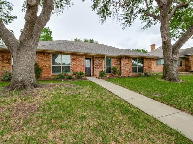 single story home with a chimney, a front lawn, and brick siding