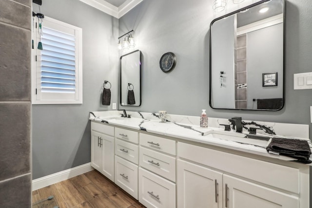 full bathroom with a sink, baseboards, double vanity, and wood finished floors