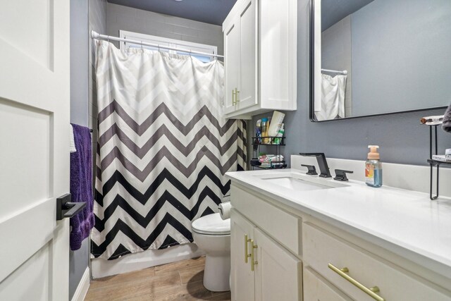 full bathroom with a shower with shower curtain, toilet, wood finished floors, and vanity