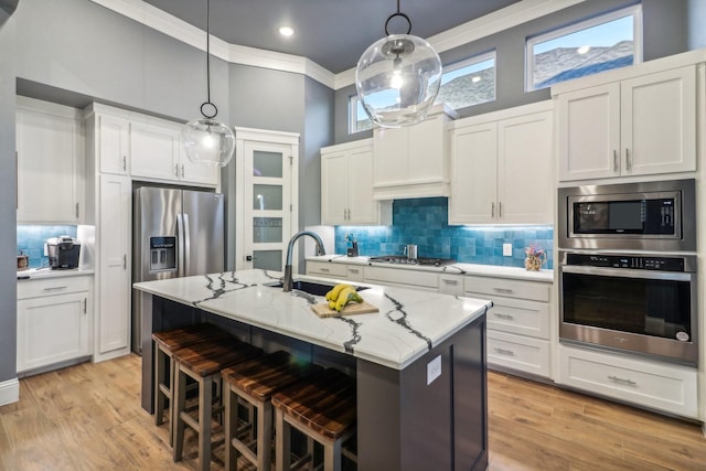 kitchen featuring decorative backsplash, a breakfast bar area, appliances with stainless steel finishes, a sink, and an island with sink