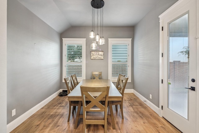 dining room featuring baseboards, light wood-type flooring, and lofted ceiling