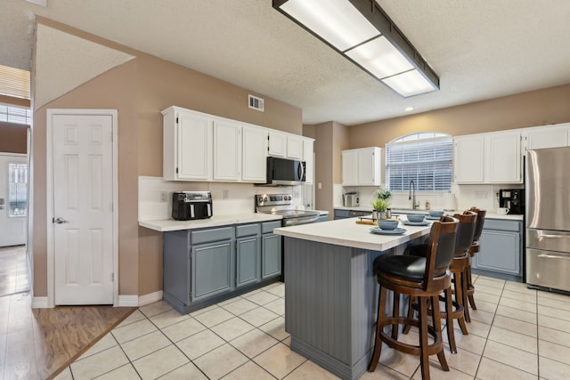 kitchen featuring gray cabinets, white cabinets, and stainless steel appliances