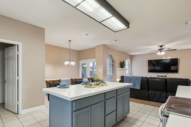 kitchen featuring a kitchen island, light tile patterned flooring, open floor plan, light countertops, and hanging light fixtures