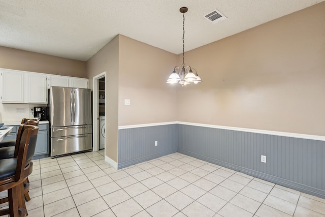 kitchen featuring white cabinets, wainscoting, freestanding refrigerator, decorative light fixtures, and visible vents