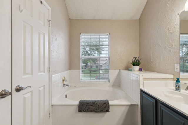 full bathroom featuring vanity, a textured wall, and a garden tub
